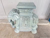 Side view of glazed ceramic elephant stool showing square top and carved details