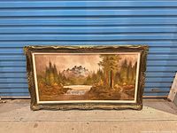 Full view of framed landscape painting against blue backdrop