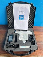 Open case showing all items: injection gun, power adapter, cords, accessories, manual