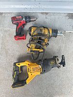 Overview of three power tools: DeWalt XR cordless reciprocating saw, DeWalt corded heat gun, red/black cordless drill-driver