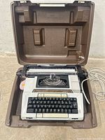 Overall view of Smith Corona Coronamatic 2200 electric typewriter seated in brown carrying case with power cord visible