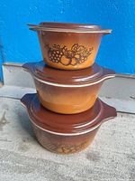 Stacked view of three Pyrex Old Orchard casseroles showing exterior pattern and graduated sizes