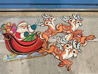 Santa in sleigh and four reindeer die-cut cardboard decoration laid out on floor