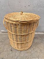 Full view of cylindrical wicker basket with lid and side handles
