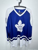 Front view of blue and white Toronto Maple Leafs jersey hanging on hanger