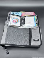 Front view of grey and black Case-it zippered binder showing mesh pocket and packaging insert