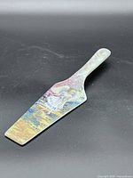 Full view of ceramic cake server showing art on blade and handle