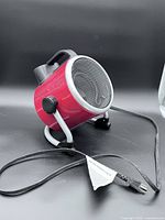 Front and side view of red cylindrical utility heater on metal stand with cord visible