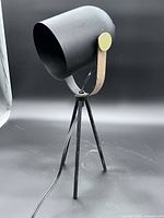 Full view of matte black tripod table lamp with cord