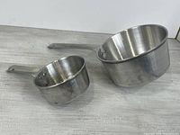 Both aluminum saucepans side by side to show size difference and condition