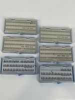 Six plastic cases of individual eyelashes arranged in two rows