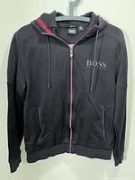 Front view of black Hugo Boss full-zip hoodie on hanger