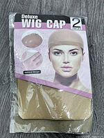 Front view of sealed pack showing beige wig caps and label