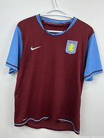 Front view of burgundy Nike Aston Villa jersey on hanger