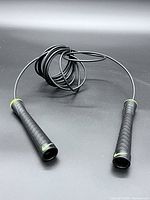Full view of black Nike jump rope coiled on surface