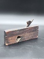 Left-side view of wooden hand plane showing blade and escapement