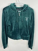 Front view of green velvet Playboy zip-up hoodie showing pockets, zipper, hood, and rhinestone logo