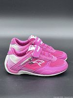 Left side view of both shoes showing pink upper, silver accents, velcro strap, side zipper pocket