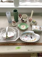 Group shot of all eleven decorative ceramic and porcelain items with ruler for scale