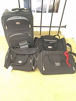 Group shot showing all four matching black American Tourister luggage pieces
