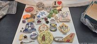 Overview of entire lot showing approximately 25 pins, buttons, badges and keychains