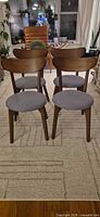Front view of all four brown wood dining chairs with gray seats