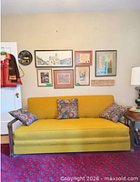 Front view of mustard yellow mid-century sofa beneath wall art