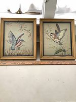 Both framed needlepoint pieces with ruler showing size