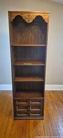Full front view of tall oak-grain laminate bookcase showing shelves and cabinet doors