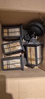 Four dark metal lantern sconces in box