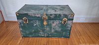 Front view of vintage green trunk with brass hardware