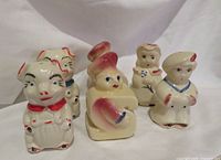 Front view of all six figural shakers showing design and paint