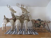 Three gold metal reindeer and matching sleigh on surface