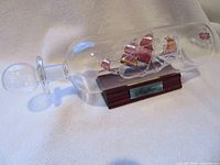 Full view of glass bottle with ship on stand