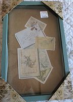 Front view of shadow box showing teal frame, glass front, interior sample cards, price tag