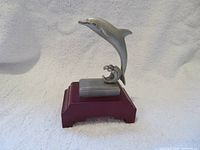 Front view of pewter dolphin on wooden stand