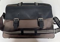 Front view of Dunhill leather and canvas duffle showing flap, buckle straps, handles, and shoulder strap