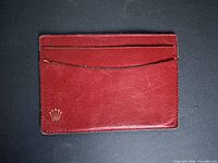 Front of red leather card holder showing gold Rolex crown and two slots