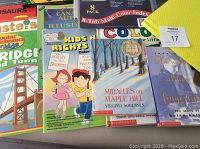 Photo of children's educational books, a multi-color tab index divider pack, and yellow lined paper packs