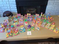 Wide view of over 30 Polly Pocket playsets arranged on table