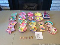 Full overview of 10 Polly Pocket compacts opened and arranged, with 5 small Polly Pocket figures in front