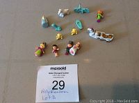 Photo showing assortment of over 10 Polly Pocket figures and accessories including characters, horse and carriage, bicycle, and duck figures.