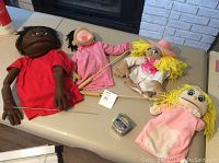Lot of four puppets showing various styles and colors, staged on a couch for scale and condition assessment.