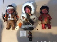 Full view of three large dolls and one small doll showing clothing and accessories
