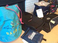 Photo showing the turquoise Barbados drawstring bag, black Jansport backpack, and several insulated lunch bags including a blue New England Patriots lunch bag