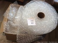 Partial roll of bubble wrap next to box filled with loose bubble wrap sheets