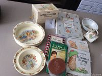 Photo shows the full set of items including boxed book, hardcover books, and china dishes decorated with Beatrix Potter characters.
