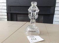 Front view of the clear glass nutcracker candle holder showing detailed features and stepped base.