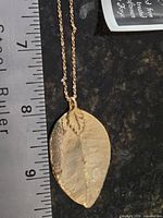 Leaf pendant beside ruler showing ~2 in. length, chain attached