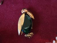 Front view showing gold-tone bird brooch with green glass belly